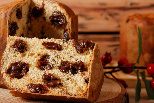 Slices of Christmas panettone with a creamy chocolate filling, displayed on a rustic table during a celebration.