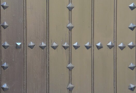 Old wooden door with geometric pattern of pyramid metal studs
