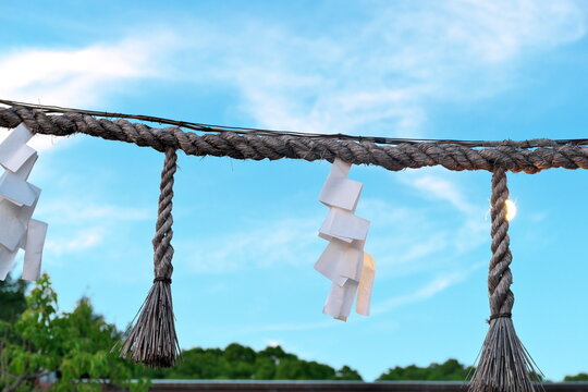 Shimenawa rope with shide against blue sky in Japan