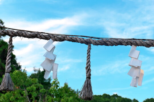 Shimenawa straw rope with shide against blue sky
