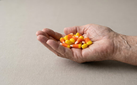 Elderly person holding candy corn in hand representing Halloween treats and aging concept