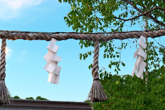 Shimenawa rope with shide against blue sky in Japan