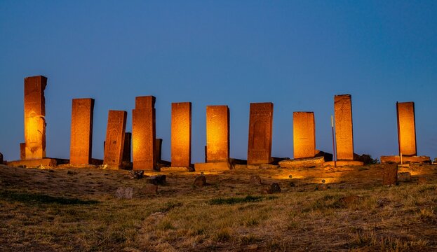 Row of historical Seljuk tombstones illuminated under the blue hour sky after sunset in the ancient Ahlat Seljuk Cemetery, Bitlis, Turkey. Long exposure shot highlighting medieval Islamic funeral arch