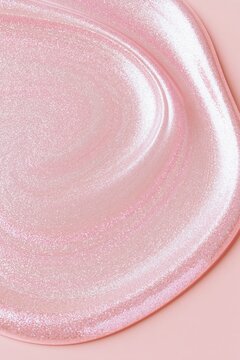 Shimmering pearlescent pink cosmetic gel texture with glossy curved highlights, creating a luxurious abstract beauty background
