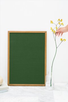 Minimal framed green board with flower stem in bright interior