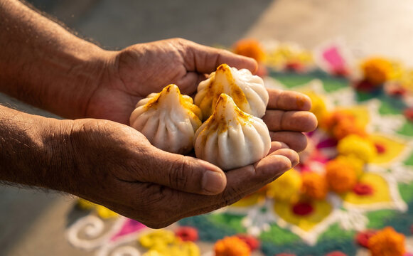 Hands holding sweet modak dumplings traditional offering for Hindu festival celebration
