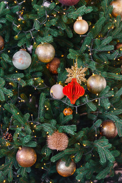 Beautifully decorated Christmas tree showcases various ornaments in shades of pink, gold, and green. Twinkling lights background enhance festive atmosphere, inviting joyful winter holiday spirit.
