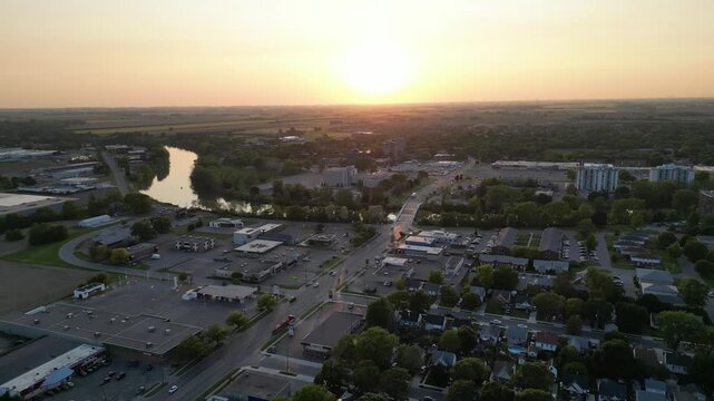 Aerial over the city of Chatham, a rural suburban community, part of the Chatham-Kent municipality. Sun and the Thames River over Keil Drive. Southwest Ontario, Canada. Sunset, May, 2023.