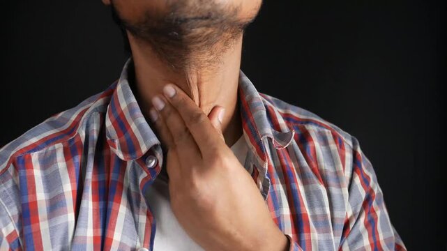 Young man experiencing discomfort in throat, indicating possible illness or health issue, static studio footage