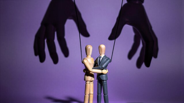 Two puppet-like businessmen are controlled by unseen hands, symbolizing manipulation.