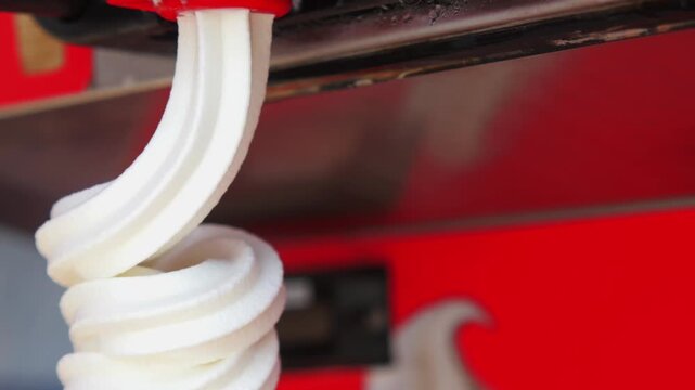 Soft serve ice cream machine pouring white vanilla milk cream into waffle cone in slow motion close up