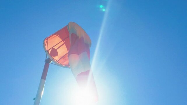 Orange and White Airport Windsock Backlit by Bright Sun Copy Space