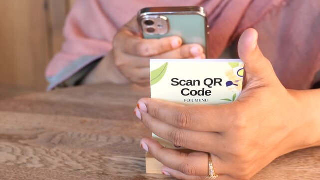 Woman scanning qr code for menu with smartphone at restaurant table dynamic motion