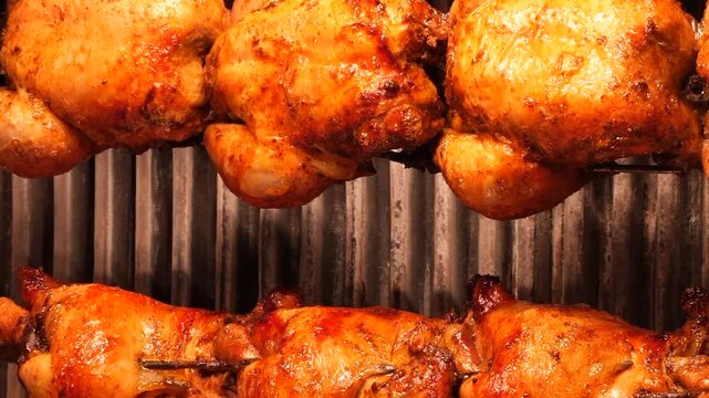 Rotisserie chicken roasting on spit in industrial oven moving in dynamic slow motion cinematic footage