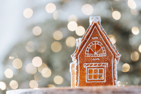  gingerbread house on a birch wood slice,Christmas setting with a glowing tree in the background.Christmas and New Year atmosphere