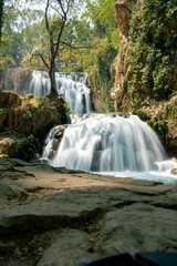 Fototapeta premium A cascade of silky water spreads over travertine steps amid moss and trees in the Monasterio de Piedra natural park in Aragon, Spain, a tranquil long exposure of a flowing waterfall.