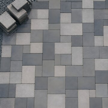Finished paving task with clean geometric stone pavers fitted tightly in repeating pattern and surplus slabs stacked nearby