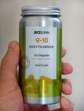 Shanghai,China-Dec.8th 2025: hand holding a bottle of BioSunn Coenzyme Q10 dietary supplement in aluminium container.