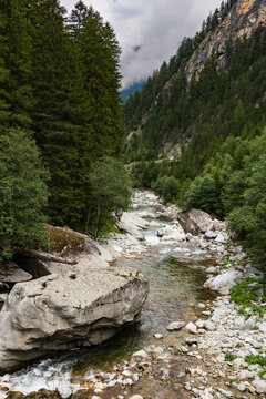 A view up the Avers Rhine river in the Magic Wood climbing area of Ausserferrera, Switzerland with a clearing storm in the mountains beyond
