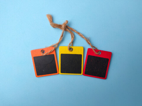 Three small blank wooden mini chalkboard tags tied with twine strings sit on a light blue background