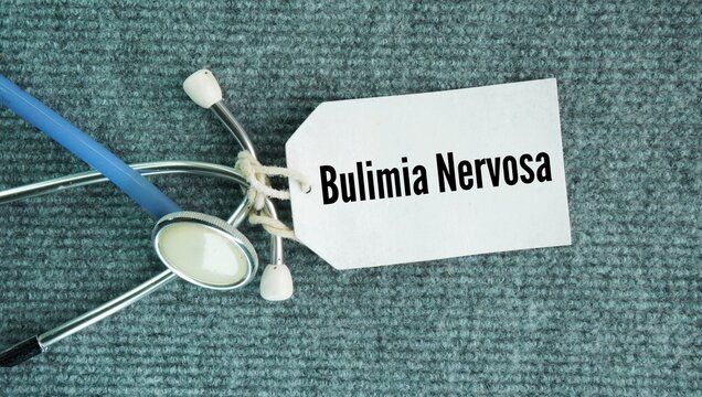 Stethoscope and paper tag with the word Bulimia nervosa. serious, potentially life-threatening eating disorder defined by a repeating cycle of eating unusually large amounts of food in a short time