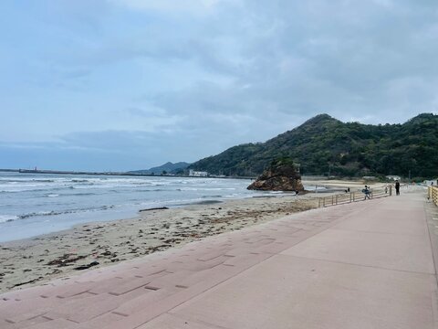 Scenic view of Inasa no Hama beach coastline and Bentenjima shrine rock under a cloudy sky