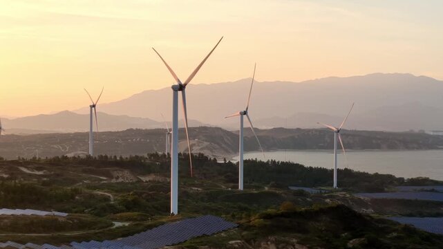 Wind turbines on hillside at sunset