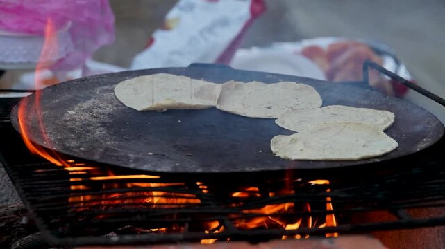 Hand Turning Corn Tortillas On Traditional Comal Over Open Fire In Rural Mexico