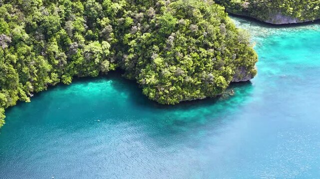 Aerial view of turquoise lagoon with tropical limestone islands and white boat in raja ampat indonesia.
