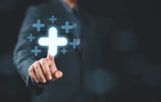 Businessman touching to plus sign mark for value added , It is symbol of business profit growth , health insurance , benefit and economy development concept.