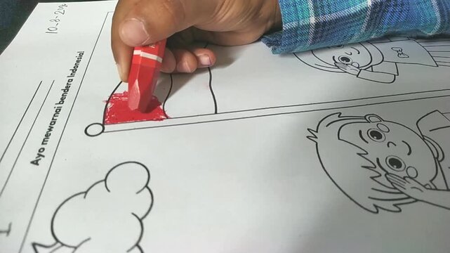 Close up child hand coloring Indonesian flag with red crayon on paper worksheet. Kids early education and patriotic activity stock footage.