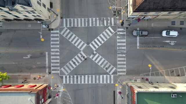 Aerial overhead drone shot over the pedestrian scramble intersection of Grand River Street and William Street in historic Paris, Ontario, Canada. Crosshatched x lines and pedestrian crosswalk.