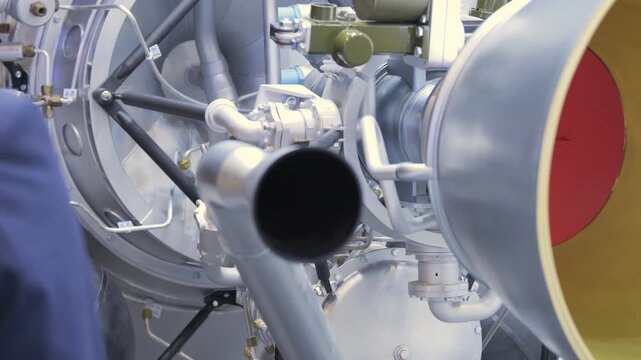 Close-up of aircraft jet engine exhaust nozzle. Metallic engine parts visible. Red and yellow painted sections. Part of aircraft engine system. Industrial aviation machinery detail