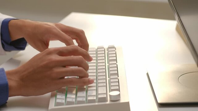Doctor in white coat typing on computer keyboard to enter electronic medical health records in hospital office