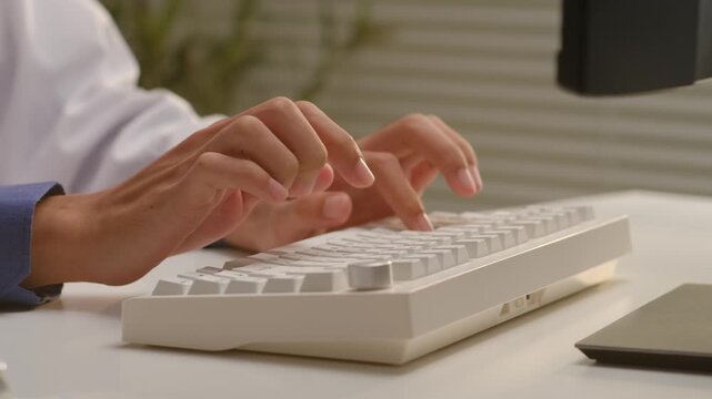 Doctor in white coat typing on computer keyboard to enter electronic medical health records in hospital office