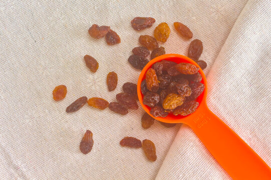 Measuring spoon of raisins on a beige cotton cloth