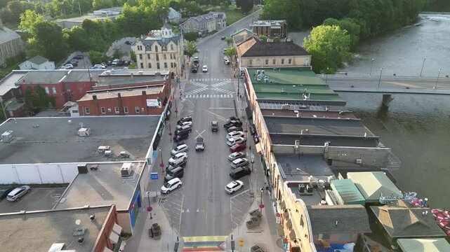 Aerial drone shot over historic downtown Paris, following Grand River Street, moving back. The Grand River to the right as it winds through Paris, Ontario, Canada on a sunny summer afternoon.