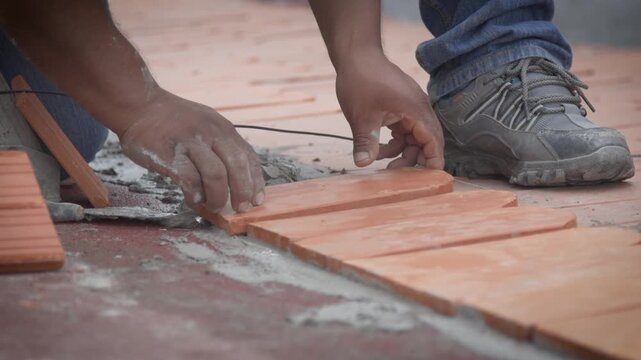 Hands positioning flat clay roof tile during installation