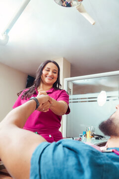 Dentist greeting patient with handshake in clinic
