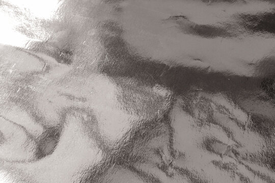 Shiny gradient silver foil texture background with uneven surface. Abstract grey foil background, metal texture wallpaper	