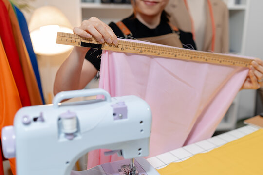 Professional fashion designer measuring fabric, selecting colors and preparing sewing equipment in a modern studio. Creative garment production, textile craftsmanship and apparel design.