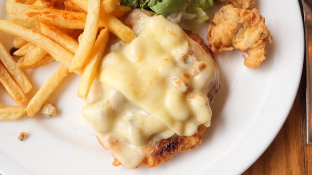 Freshly cooked chicken schnitzel topped with melted cheese served with french fries and salad