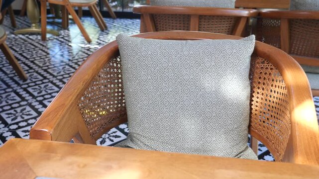 Empty outdoor cafe chair with patterned pillow and rattan back, slow motion