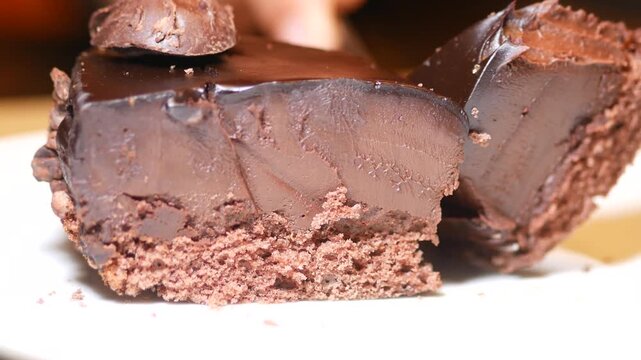 Delicious chocolate cake slice with glossy topping being cut with a fork slow motion