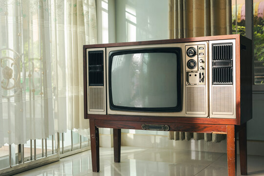 Old-fashioned retro-style television with a blank screen stands in a living room at home.