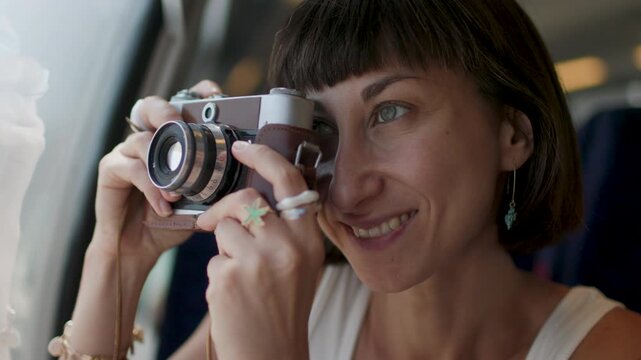 Girl tourists, travels and smiles she uses a camera to take photos on the train. summer trip.