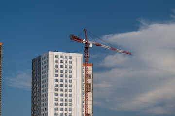 Construction site bustling with activity under a bright blue sky showcasing a towering crane against modern buildings in progress © beholdereye