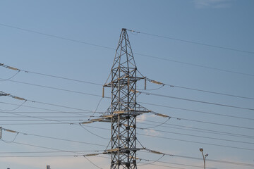 Power tower stands tall against a clear sky showcasing the intricate web of high voltage lines connecting cities and communities © beholdereye