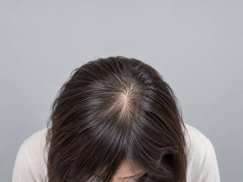前かがみになって頭頂部のつむじを見せる女性