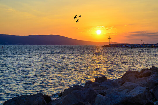 Golden sunset over the Black Sea coast in Nessebar with birds flying in the sky, Bulgaria